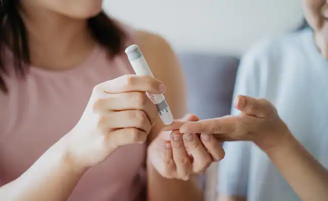 Doctor examining blood sugar level with a needle: Insights into the connection between diabetes and eyesight.
