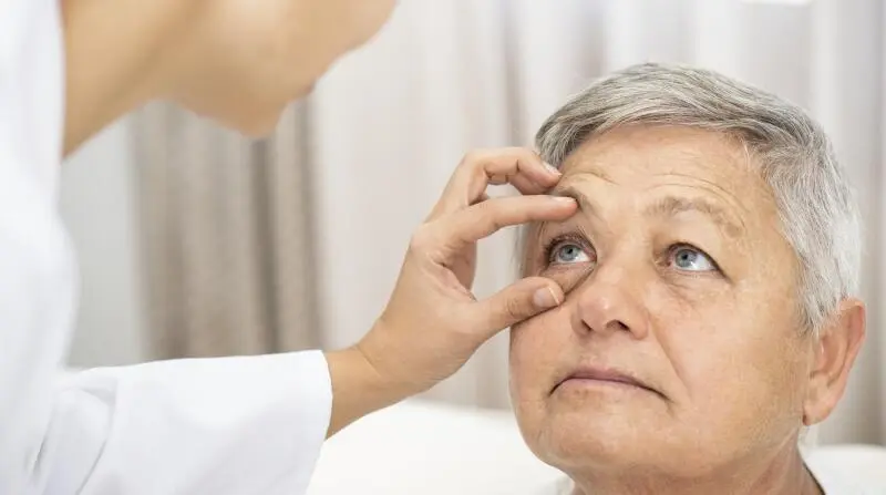 Professional ophthalmologist conducting a thorough follow-up visit after cataract surgery for an elderly female patient. Ensuring post-operative care and monitoring for a successful recovery.