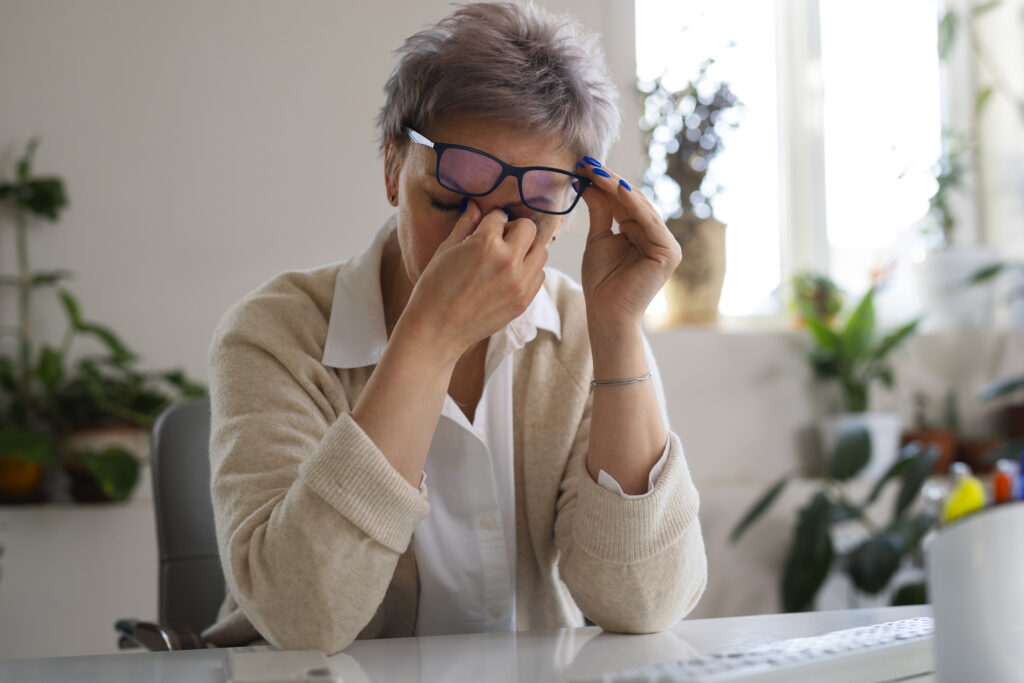 Woman rubbing eyes from vision strain, symbolizing cataract progression to blindness.