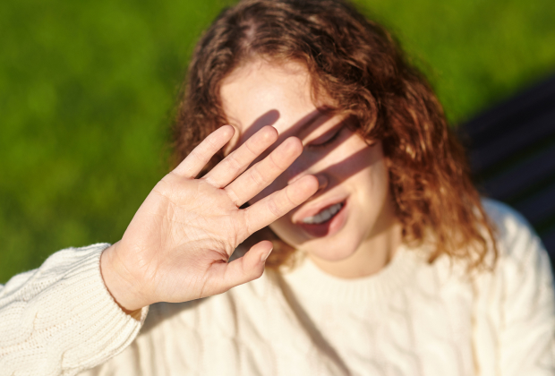 A women shielding her face from the sunlight, demonstrating light sensitivity in her eyes